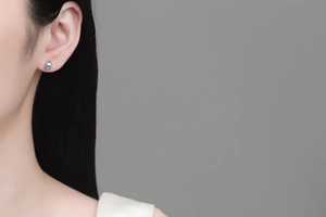 Close-up of a minimalist silver stud earring with a small crystal on female ear
