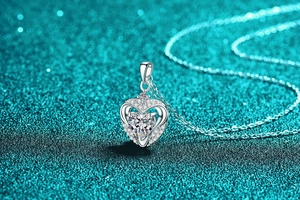 Macro detail of S925 sterling silver heart necklace with sparkling moissanite on blue background