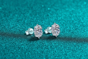 Detailed view of sterling silver moissanite stud earrings with halo setting on glittery background