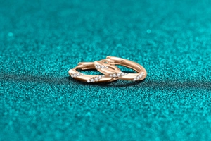 Macro shot of rose gold hoop earrings with twisted design and pavé diamond details