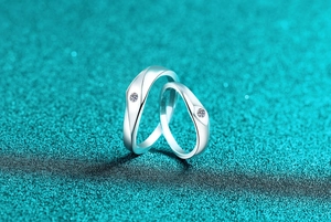 Macro shot of silver moissanite couple rings with wavy band and sparkling center stones