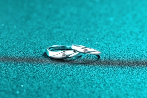Macro shot of silver moissanite couple rings with twisted bands on a blue background