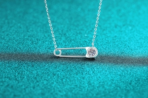 Gros plan du collier épingle de sûreté en argent S925 et moissanite sur bleu