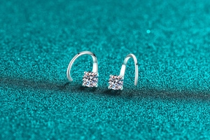 Détail de boucles d'oreilles en argent S925 et moissanite avec crochets sur fond texturé