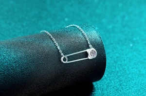 Détail du collier épingle de sûreté en argent S925 avec moissanite sur socle noir et fond vert