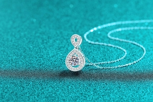 Macro del ciondolo a goccia in argento S925 con moissanite su sfondo glitter blu mare