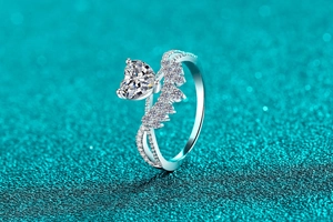 Macro view of heart-shaped moissanite ring with interlaced pavé diamond band on teal background