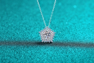 Dettaglio macro del ciondolo girasole in moissanite con catena in argento su fondo blu
