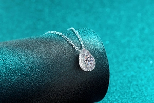 Macro detail of teardrop pear-shaped moissanite pendant with sparkling cluster setting