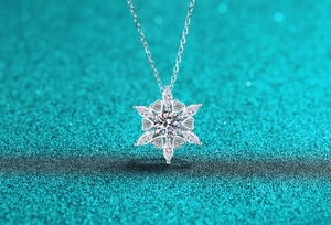 Detailed view of S925 silver snowflake pendant with sparkling moissanite on blue background