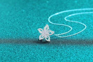 Gros plan du pendentif fleur en argent 925 avec moissanite sur fond bleu scintillant