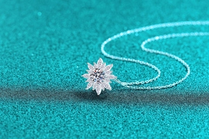 Vista macro della collana girasole in argento S925 con moissanite su sfondo glitter blu
