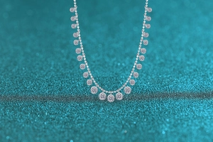 Macro shot of S925 sterling silver necklace featuring round moissanite charms on blue glitter