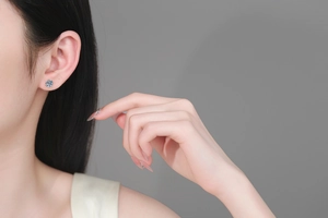 Close-up of minimalist S925 sterling silver four-prong stud earring on model's ear