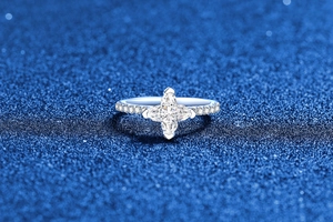 Macro d'une bague en argent 925 avec moissanite étoile trèfle sur un fond bleu foncé