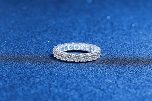 Macro shot of silver eternity ring with pavé moissanite stones on sparkling blue surface