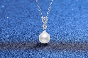 Macro detail of S925 sterling silver infinity necklace featuring a white pearl and moissanite