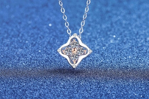 Close-up of sparkling four-leaf clover moissanite pendant in two-tone sterling silver