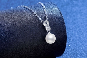 Macro shot of s925 silver infinity necklace featuring a large lustrous white pearl pendant
