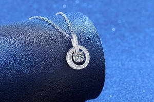 Macro shot of sparkling moissanite pendant with double ring setting on blue jewelry stand