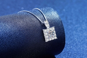 Macro view of 1ct moissanite square pendant with brilliant halo and silver box chain