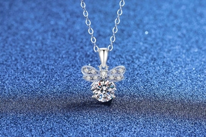 Macro shot of silver bee pendant with moissanite center stone and pavé diamond wings