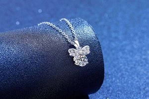 Detailed view of s925 silver bow pendant with sparkling moissanite on blue stand