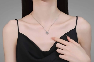 Detailed close-up of S925 silver clover necklace with blue stone on a female neck