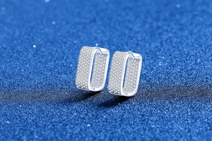 Macro shot of silver U-shaped earrings with full pave cubic zirconia on a blue background