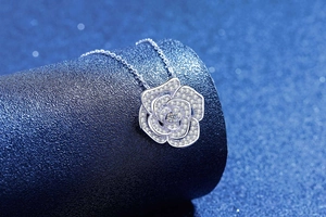 Détail macro du pendentif camélia en argent avec pavé de moissanite et pierre centrale