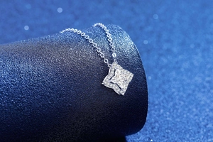 Macro side view of silver S925 moissanite clover pendant on a blue star display base