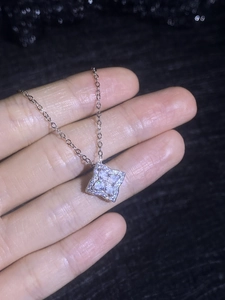 Macro shot of silver four-leaf clover pendant with sparkling 1ct moissanite center stone