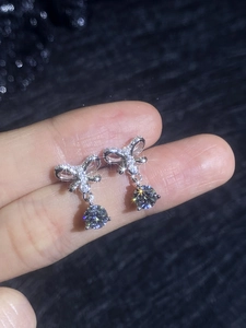 Vue macro de boucles d'oreilles nœud en argent avec pendentif moissanite sur fond sombre