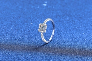 Macro detail of square halo moissanite ring with round center stone and diamond band