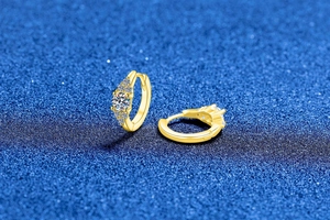 Vue macro de boucles d'oreilles créoles dorées avec moissanite et serti à griffes