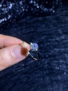 Macro shot of a 1 carat round moissanite ring with a classic four-prong silver setting