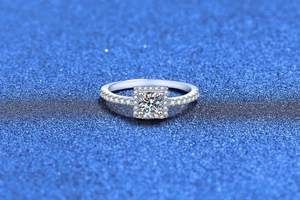 Macro detail of a halo setting Moissanite ring with side diamonds on blue sparkle background