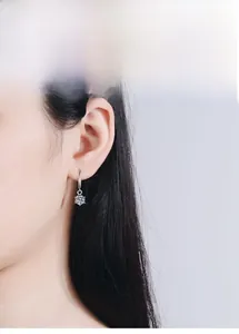 Eleganti orecchini pendenti in argento s925 con moissanite indossati da una modella su grigio