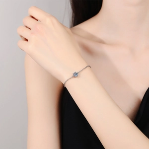 Classic moissanite six-prong silver bracelet on a female model with a sleek chain