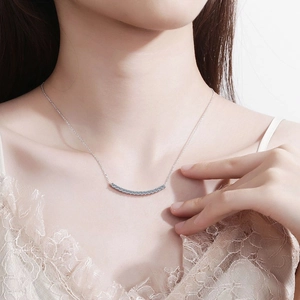 Close-up of a sparkling moissanite smile pendant necklace worn on a woman's collarbone