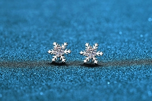 Close-up of snowflake Moissanite stud earrings in S925 sterling silver on blue background