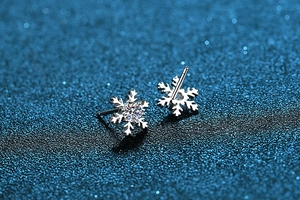 Macro view of snowflake moissanite earrings in S925 sterling silver on blue background