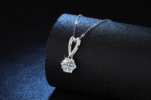 Detailed close-up of heart-shaped clasp and snowflake-set moissanite on silver necklace