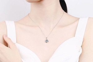 Close-up of 925 silver necklace with sparkling clover moissanite pendant on a female neck