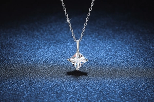 Détail macro du pendentif en moissanite taille princesse avec serti griffes en argent sur fond bleu