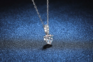 Macro shot of 1ct moissanite pendant with three accent diamonds on blue background
