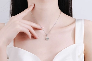 Gros plan d'un pendentif trèfle en argent S925 avec moissanite porté par un mannequin