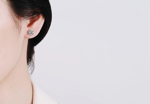Close-up of a 6-prong silver stud earring with a brilliant round moissanite stone