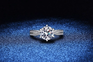 Macro detail of a 6-prong moissanite ring with split shank and diamond pavé settings