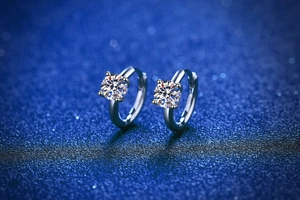 Detailed view of silver moissanite earrings with four-prong setting on a bokeh background